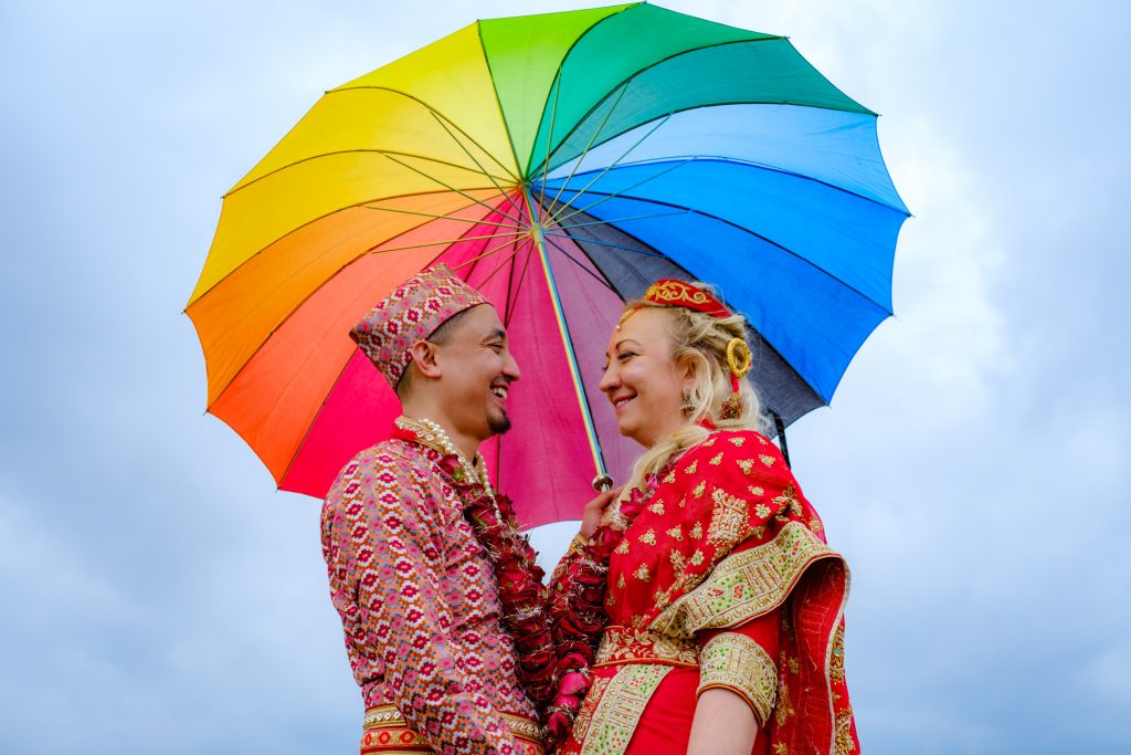 A Nepalese wedding couple under a multicolored umbrella